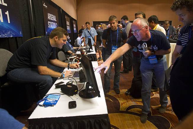 Glenn Wilkenson, left, of SensPost, an information security company, demonstrates a technique for collecting unique, identifiable information from mobile devices during the Black Hat USA 2014 hacker conference at the Mandalay Bay Convention Center Aug. 6, 2014.