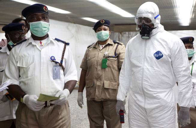 Nigerian health officials wait to screen passengers for Ebola at the arrivals hall of Murtala Muhammed International Airport in Lagos, Nigeria, Monday, Aug. 4, 2014.
