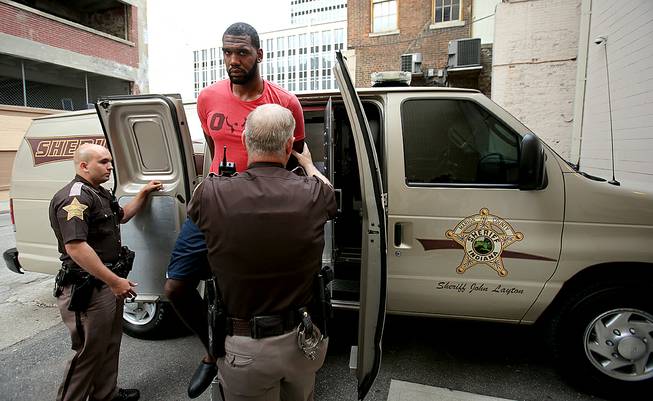 Greg Oden is escorted into the Marion County Community Corrections building, Thursday, Aug. 7, 2014, in Indianapolis. Police arrested former NBA No. 1 draft pick Greg Oden on battery charges early Thursday, alleging that he punched his ex-girlfriend in the face during a fight at his mother's suburban Indianapolis home. 