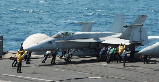This image released by the U.S. Navy shows sailors guiding an F/A-18C Hornet assigned to the Valions of Strike Fighter Squadron 15 on the flight deck of the aircraft carrier USS George H.W. Bush on Thursday, Aug. 7, 2014, in the Persian Gulf.