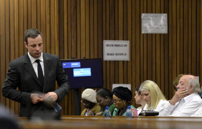 Oscar Pistorius, left, walks past Barry Steenkamp, the father of Reeva Steenkamp, right, during his trial, in Pretoria, South Africa, Friday, Aug. 8, 2014. The chief defense lawyer for Pistorius delivered final arguments in the athlete's trial on Friday, alleging that Pistorius thought he was in danger when he killed girlfriend Reeva Steenkamp and also that police mishandled evidence at the house where the shooting happened.