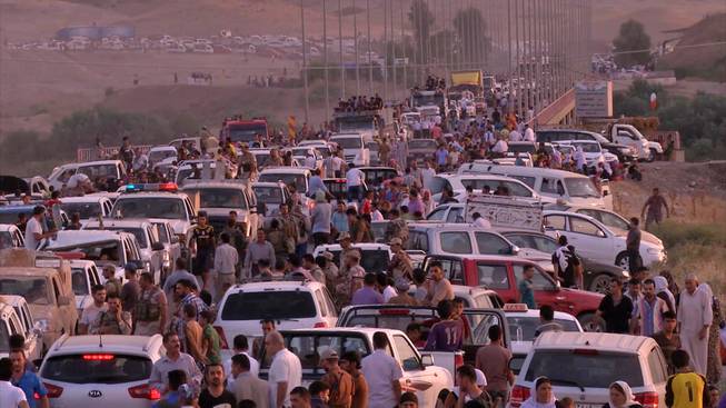 This image made from video taken on Sunday, Aug. 3, 2014, shows Iraqis people from the Yazidi community arriving in Irbil in northern Iraq after Islamic militants attacked the towns of Sinjar and Zunmar. Around 40 thousand people crossed the bridge of Shela in Fishkhabur into the Northern Kurdish Region of Iraq, after being given an ultimatum by Islamic militants to either convert to Islam, pay a security tax, leave their homes, or die.