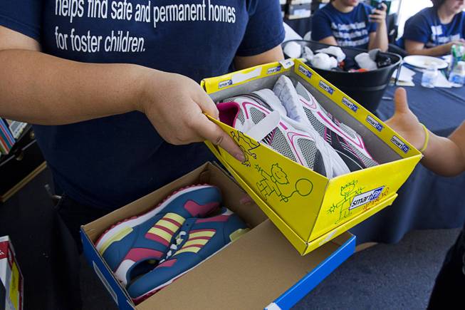 A volunteer hands out shoes, courtesy of Zappos, during a special back-to-school event for foster children at Square Salon, 1225 South Fort Apache Blvd., during a Sunday, August 10, 2014. The event was sponsored by the CASA Foundation, a local non-profit organization, in partnership with Square Salon and other organizations.