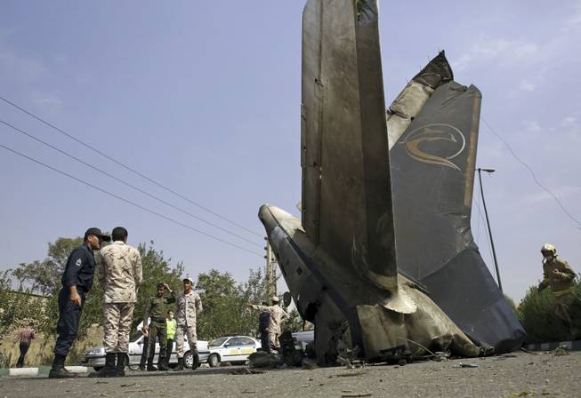 Iranian Revolutionary Guards inspect the site of a passenger plane crash near the capital Tehran, Iran, Sunday, Aug. 10, 2014. An Iranian passenger plane crashed Sunday while taking off from an airport near the capital, Tehran, killing tens of people onboard, state media reported.