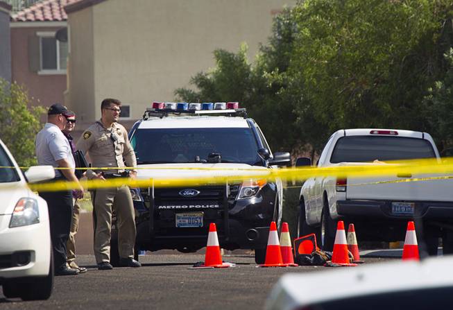 Metro Police investigators stand by the scene of an officer-involved shooting in the 7600 block of Calico Fields Street, near Fort Apache and Farm roads Monday, Aug. 11, 2014. Police said a suspect was shot after officers responded about 1 p.m. to a disturbance call.