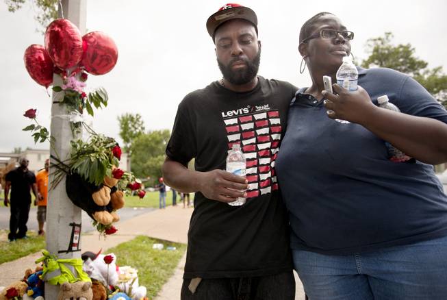 Mourners embrace at a spontaneous memorial for shooting victim Michael Brown, 18, Sunday, Aug. 10, 2014 at the scene of the shooting in Ferguson, Mo. Police said Brown, who was unarmed, was fatally shot Saturday in a scuffle with an officer.