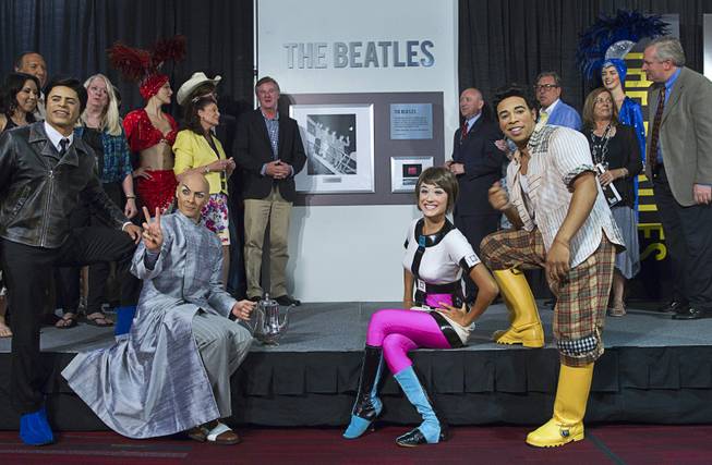 Cirque du Soleil performers from the Love show and others pose in front of a commemorative plaque during a news conference in the lobby of the Las Vegas Convention Center Tuesday, Aug. 12, 2014. The event celebrated the 50th anniversary of the Beatles concert in Las Vegas on August 20, 1964.