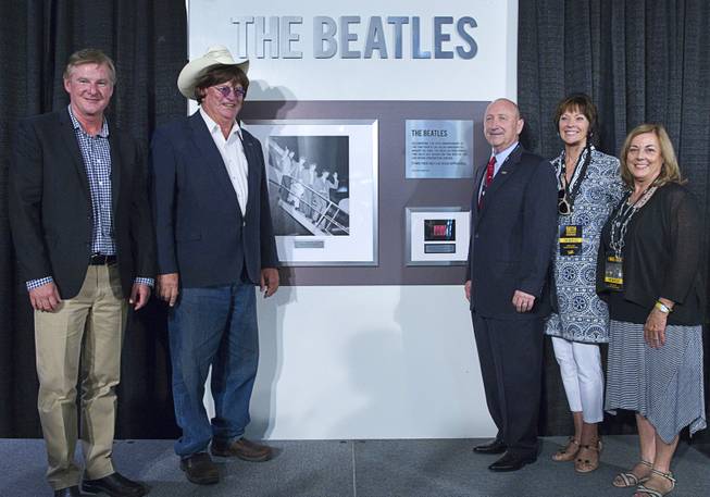 From left: author Chuck Gunderson, Clark County Commissioner Tom Collins, Rossi Ralenkotter, left, president/CEO of the Las Vegas Convention and Visitors Authority (LVCVA), his wife Mary Jo Ralenkotter, and Violet Hawkes pose in front of a commemorative plaque during a news conference in the lobby of the Las Vegas Convention Center Tuesday, Aug. 12, 2014. The event celebrated the 50th anniversary of the Beatles concert in Las Vegas on August 20, 1964.
