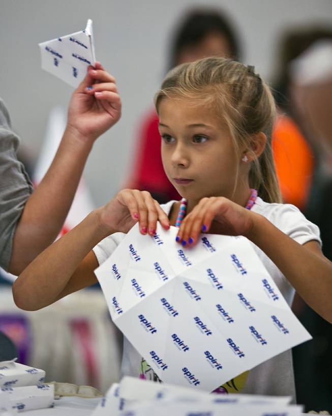 Brooklyn Jimenez, 8, with team Spirit joins others in folding their airplanes before the Paper Plane Palooza competition begins at McCarran International Airport on Tuesday, August 12, 2014.