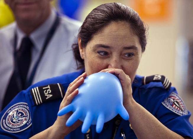 A TSA agent blows up a glove into a balloon to entertain the kids before the Paper Plane Palooza competition begins at McCarran International Airport on Tuesday, August 12, 2014.