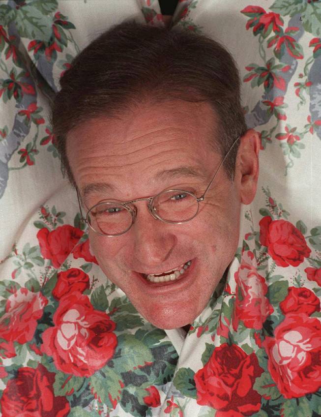 In this Nov. 15, 1997 file photo, Robin Williams extends his head between curtains in a New York hotel. Williams, a brilliant shapeshifter who could channel his frenetic energy into delightful comic characters like "Mrs. Doubtfire" or harness it into richly nuanced work like his Oscar-winning turn in "Good Will Hunting," died Monday in an apparent suicide. He was 63. Williams was pronounced dead at his San Francisco Bay Area home Monday, according to the sheriff's office in Marin County, north of San Francisco. 