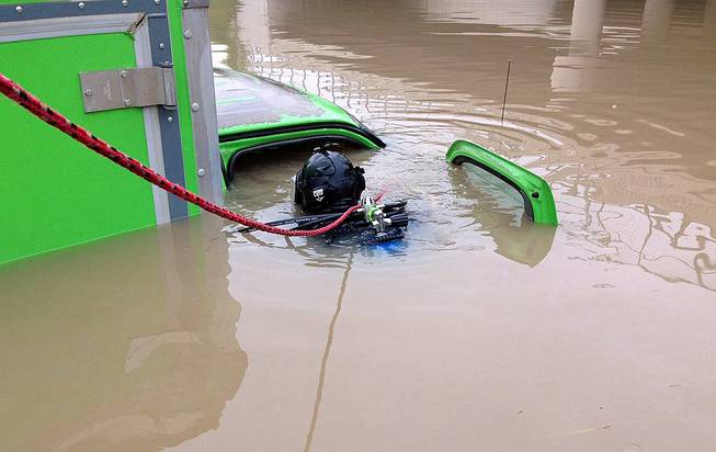 In a photo provided by the Michigan State Police, a diver with the department's Underwater Recovery Unit inspects a vehicle, Tuesday, Aug. 12, 2014, submerged on a Detroit area freeway a day after heavy of rain. 