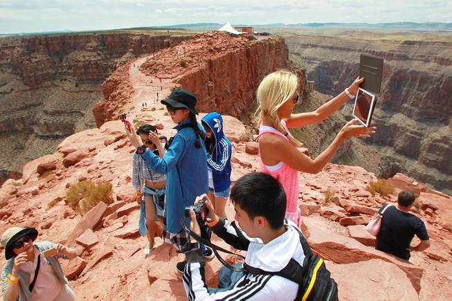 Tourists take photos at Guano Point at Grand Canyon West Tuesday, Aug. 12, 2014.