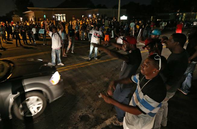 A group demonstrates along and in the middle of Chambers Road outside the Greater St. Mark Missionary Baptist Church after the conclusion of a gathering with Michael Brown's family and Rev. Al Sharpton on Tuesday, Aug. 12, 2014, in Dellwood. The gathering at the church was in response to the police shooting of 18-year-old Michael Brown on Saturday.