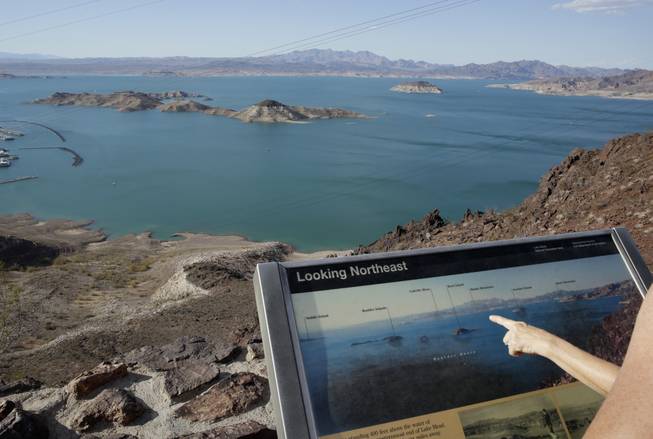 In this July 24, 2014, photo, dropping water levels reveal larger islands in Lake Mead compared to a picture on an interpretive sign on a hill overlooking the lake in Lake Mead National Recreation Area.