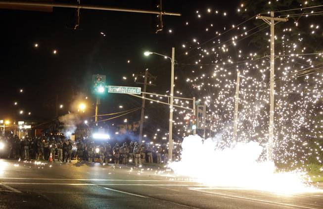 A device deployed by police goes off in the street as police and protesters clash Wednesday, Aug. 13, 2014, in Ferguson, Mo. Authorities in the St. Louis suburb where an unarmed black teen was shot and killed by a police officer have used tear gas to try to disperse protesters after flaming projectiles were thrown from the crowd.
