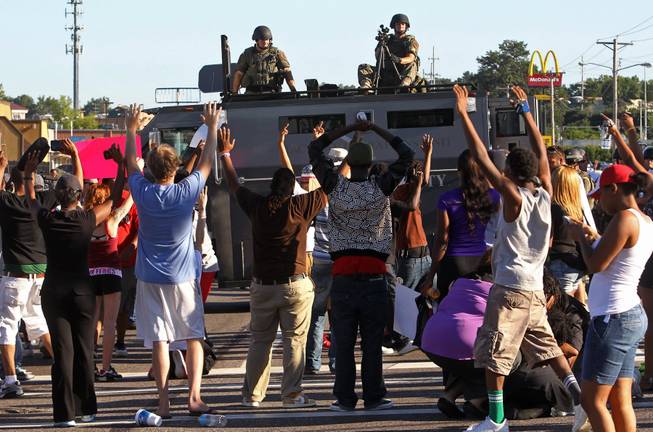 Protesters raise their hands in front of police atop an armored vehicle in Ferguson, Mo. on Wednesday, Aug. 13, 2014. On Saturday, Aug. 9, 2014, a police officer fatally shot Michael Brown, an unarmed black teenager, in the St. Louis suburb.