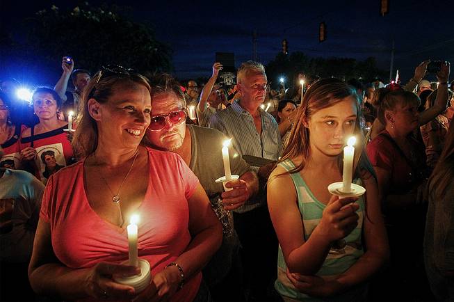 Sharon Kestner, left, enjoys the sounds of Elvis, as Brian Bush rests his head on her shoulder outside the gates of Graceland during a candlelight vigil in remembrance of Elvis’ death 37 years-ago, Friday, Aug. 15, 2014, in Memphis, Tenn. Kestner and Bush are from Lexington, Ky. 