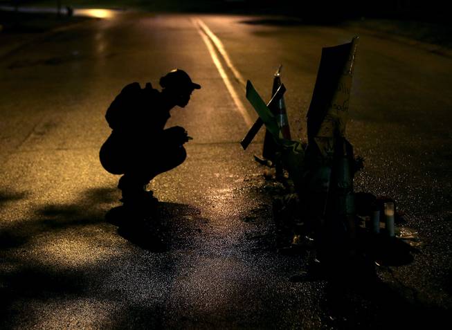 Ty Crustfield pauses, Friday, Aug. 15, 2014, before a makeshift memorial in the middle of the street where Michael Brown was killed by police nearly a week ago in Ferguson, Mo.