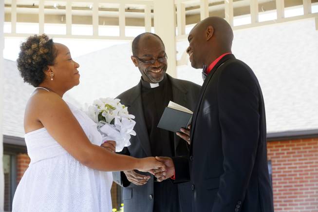Pastor Robert Davis, the father of the groom, center, conducts the marriage ceremony between Miriam Reeves, left, and Mark Davis beneath the gazebo in the courtyard of Foundation Park Alzheimer's Care on Saturday, Aug. 16, 2014. 