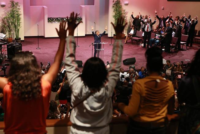 The Rev. Al Sharpton raises his hands with the crowd during a service for the Michael Brown family at the Greater Grace Church in Ferguson, Mo. on Sunday, Aug. 17, 2014. On Saturday, Aug. 9, 2014, a white police officer fatally shot Brown, an unarmed black teenager, in the St. Louis suburb. 