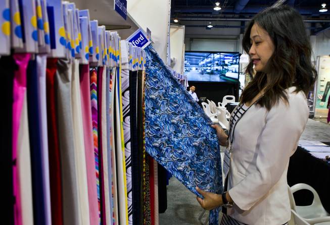 Emily Huang sorts through fabrics on display as senior project manager with Ashford Textiles during the MAGIC Marketplace Fall Show at the Las Vegas Convention Center on Tuesday, August 19, 2014.