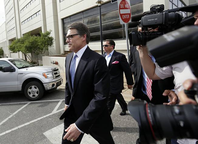 Texas Gov. Rick Perry, left, leaves the Blackwell Thurman Criminal Justice Center after he was booked, Tuesday, Aug. 19, 2014, in Austin, Texas. Perry was indicted last week on charges of coercion and official oppression for publicly promising to veto $7.5 million for the state public integrity unit run.