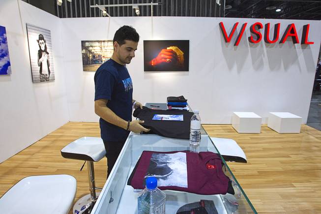 Navid Saedi, a marketing associate with Visual, folds T-shirts during the Modern Assembly fashion trade show at the Sands Expo & Convention Center Wednesday, Aug. 20, 2014. The company was started by photographer Van Styles so the booth was created with an Art Gallery feel, Saedi said. The show is a collection of six shows: The Accessories Show, Agenda, Capsule, Liberty, Mrket, and Stitch.