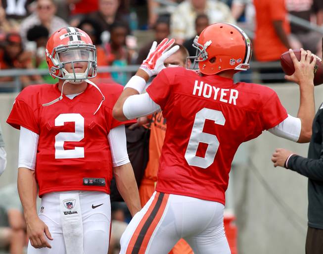 In this Aug. 2, 2014, photo, Cleveland Browns quarterback Brian Hoyer throws a pass as Johnny Manziel watches at NFL practice at InfoCision Stadium in Akron, Ohio.