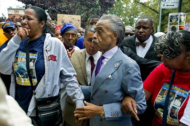 Esaw Garner, left, arrives at the spot where her husband Eric Garner died with The Rev. Al Sharpton, center, and Eric Garner's mother Gwen Carr, right, at the start of a march and rally in the Staten Island borough of New York, Saturday, Aug. 23, 2014. The city medical examiner ruled that Eric Garner, 43, died as a result of a police chokehold during an attempted arrest. 