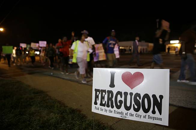 Protesters march Thursday, Aug. 21, 2014, in Ferguson, Mo. Protesters again gathered Thursday evening, walking in laps near the spot where Michael Brown was shot. Some were in organized groups, such as clergy members. More signs reflected calls by protesters to remove the prosecutor from the case. 
