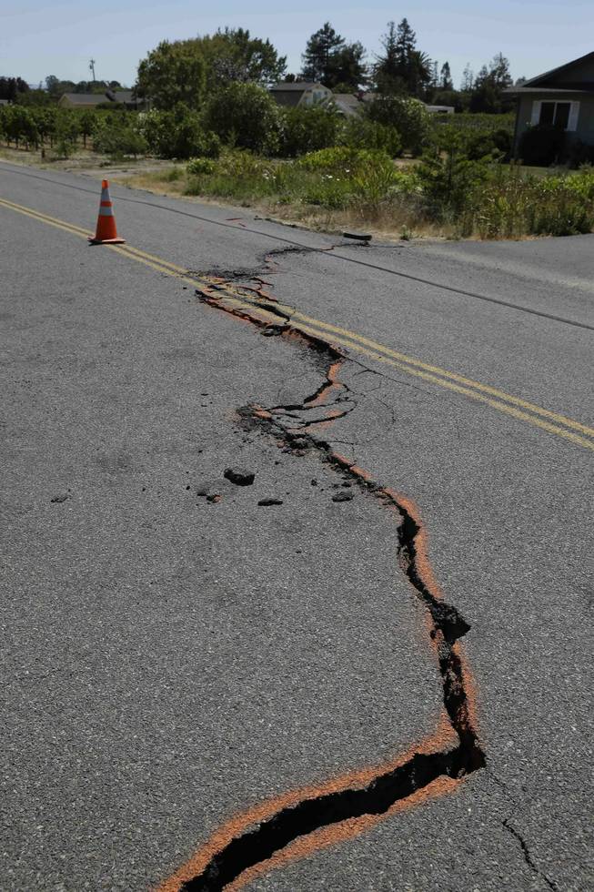 A cracked section of roadway is shown in the Carneros district following an earthquake Sunday, Aug. 24, 2014, in Napa, Calif. The largest earthquake to hit the San Francisco Bay Area in 25 years struck before dawn on Sunday, sending scores of people to hospitals, igniting fires, damaging historic buildings and knocking out power to thousands of homes and businesses in California's wine country.