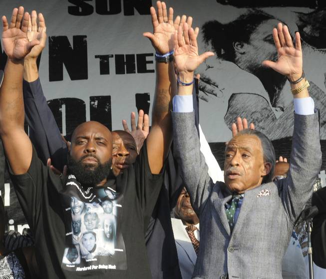 Father of slain teen Michael Brown, Michael Brown, Sr., left, and Reverend Al Sharpton, right, gesture to the crowd at Peace Fest, Sunday, Aug. 24, 2014, in St. Louis. Tomorrow all I want is peace," Brown Sr. told hundreds of people in St. Louis’ largest city park Sunday during brief remarks at a festival that promoted peace over violence.