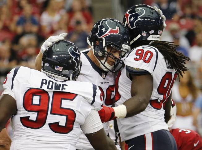 Houston Texans defensive end J.J. Watt, center, celebrates his sack with teammates Jadeveon Clowney (90) and Jerrell Powe (95) during the first half of an NFL preseason football game against the Arizona Cardinals, Saturday, Aug. 9, 2014, in Glendale, Ariz.