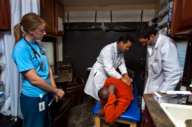 (From left) Student physician assistant Dode Cairncross observes as faculty Dr. David Park works on the back of patient Rene King with resident Dr. Badi Eghterafi on hand within the Touro University Nevada Mobile Healthcare Clinic on Wednesday, August 27, 2014. King was receiving an osteopathic manipulative treatment and felt much better afterwards.