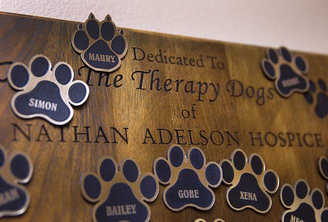 Paw badges are shown on a dedication board at the Nathan Adelson Hospice in Mountain View Medical Center Wednesday, Sept. 3, 2014. Therapy dogs (and one cat - top left, now retired) get their badges posted on the board after on year of service.