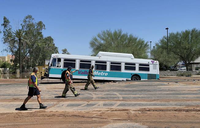 A valley metro bus sits mired in a collapsed, muddy street after a water main break flooded the area, Wednesday, Sept. 3, 2014 in Tempe, Ariz. Police say police officers and firefighters helped passengers get off the bus and that nobody was injured during the Wednesday morning incident though some businesses were flooded. 