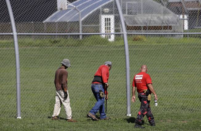 A crew checks for weak spots in the fence surrounding the Woodland Hills Youth Development Center Tuesday, Sept. 2, 2014, in Nashville, Tenn. According to a Department of Children's Services spokesman, more than 30 teenagers escaped from the facility Monday night by overwhelming 16 to 18 staff members, then crawling under a weak spot in the fence. 