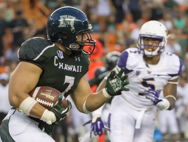 Hawaii running back Joey Iosefa (7) looks for an opening as Washington defensive lineman Joe Mathis (5) watches the third quarter of an NCAA college football game, Saturday, Aug. 30, 2014, in Honolulu. (