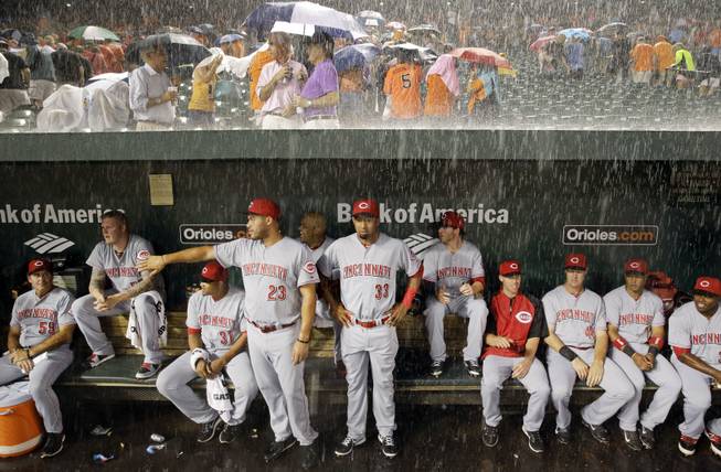 AP10ThingsToSee- Members of the Cincinnati Reds watch from the dugout as heavy rain falls during a rain delay in the first inning of an interleague baseball game against the Baltimore Orioles, Tuesday, Sept. 2, 2014, in Baltimore. 