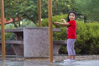 Judith Torres, 4, catches rain drops from the shelter of a picnic area at Exploration Park in the Mountain's Edge master-planned community during Sunday's rainstorm, Sept. 7, 2014.