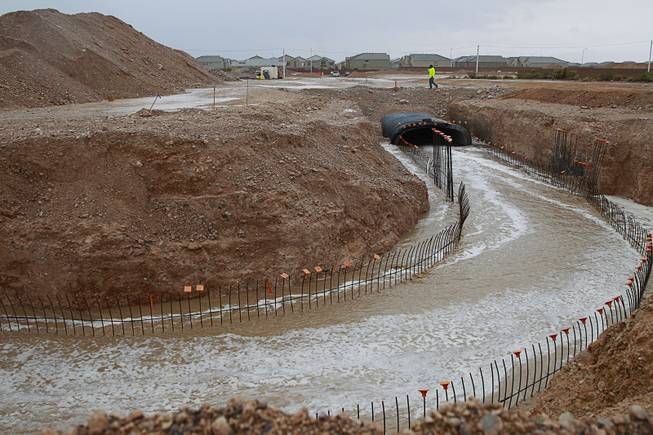 Rain runoff flows down an unfinished flood control project near Blue Diamond Road and Grand Canyon Monday, Sept. 8, 2014.  