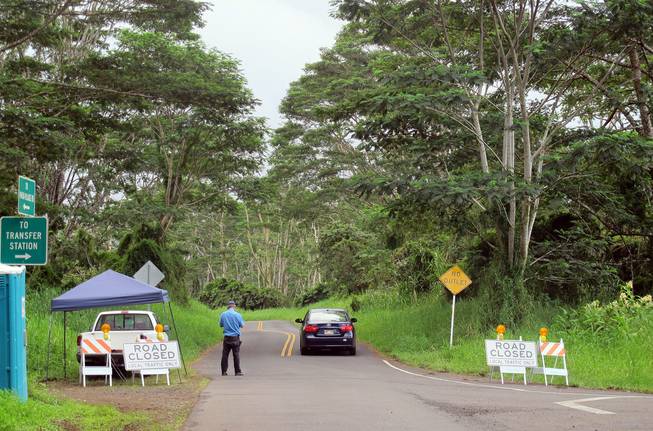 In this Monday, Sept. 8, 2014, photo, a guard stands at the entry to the Kaohe Homesteads community in Pahoa, Hawaii, where only residents are allowed to enter because of threat of lava flows. Those who live on the slopes of Kilauea volcano know lava could start creeping their way at any time, but the area is still a powerful draw for many who value its community and affordability.