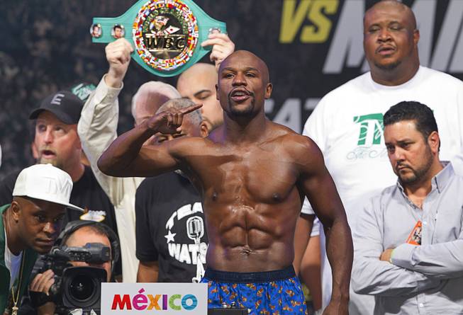 WBC/WBA welterweight champion Floyd Mayweather Jr.  poses on the scale during an official weigh-in at the MGM Grand Garden Arena  Friday, Sept. 12, 2014. Mayweather Jr. will defend his titles against Marcos Maidana of Argentina at the arena on Saturday.