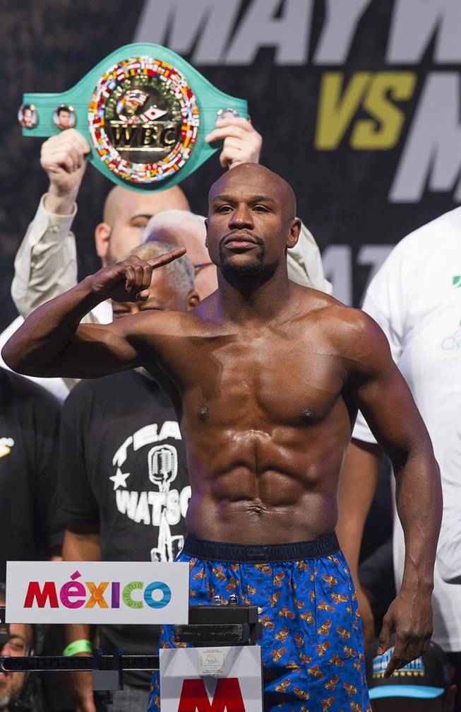 WBC/WBA welterweight champion Floyd Mayweather Jr.  poses on the scale during an official weigh-in at the MGM Grand Garden Arena  Friday, Sept. 12, 2014. Mayweather Jr. will defend his titles against Marcos Maidana of Argentina at the arena on Saturday.
