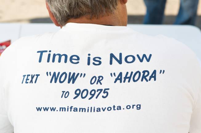 The slogan for Mi Familia Vota is seen on the back of Miguel Amaral's shirt, a field registrar attempting to register voters outside the E. Saraha DMV, Friday Sept. 12, 2014.
