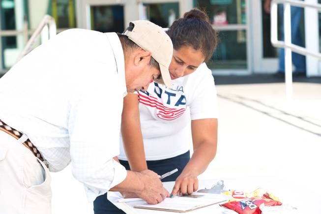 Stephanie DeJesus, at right, helps a voter fill out a registration form outside the E. Saraha DMV, Friday Sept. 12, 2014. DeJesus is a field registrar for Mi Familia Vota, a non-partisan organization that encourages civic engagement among the Hispanic community.
