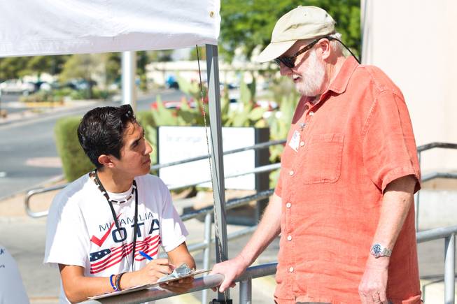 Francisco Gonzalez, at left, helps a voter fill out a registration form outside the E. Saraha DMV, Friday Sept. 12, 2014. Gonzalez is a Canvas Lead at Mi Familia Vota, a non-partisan organization that encourages civic engagement among the Hispanic community.