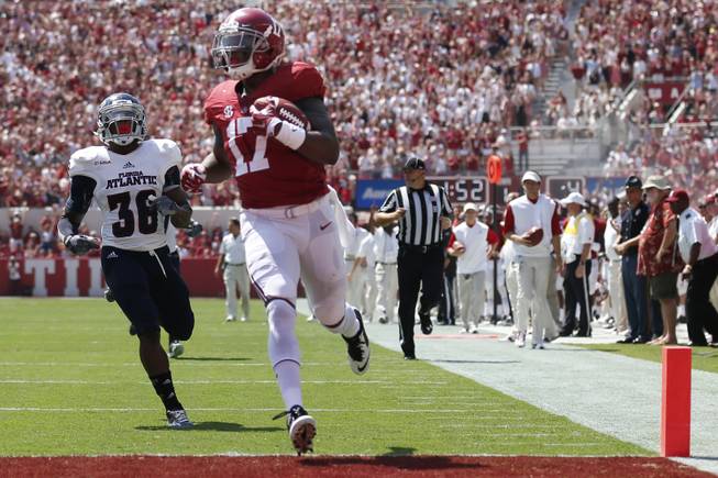 Alabama running back Kenyan Drake (17) scores a touchdown in front of Florida Atlantic defensive back Anthony Hamilton (36) in the first half of an NCAA college football game  Saturday, Sept. 6, 2014, in Tuscaloosa, Ala. (AP Photo/Brynn Anderson)