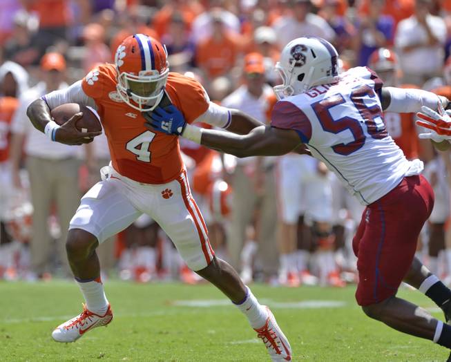 Clemson quarterback Deshaun Watson runs out of the pocket and is pressured by South Carolina State's Alexander Glover during an NCAA college football game in Clemson, S.C.,  Saturday, Sept. 6, 2014.  (AP Photo/ Richard Shiro)